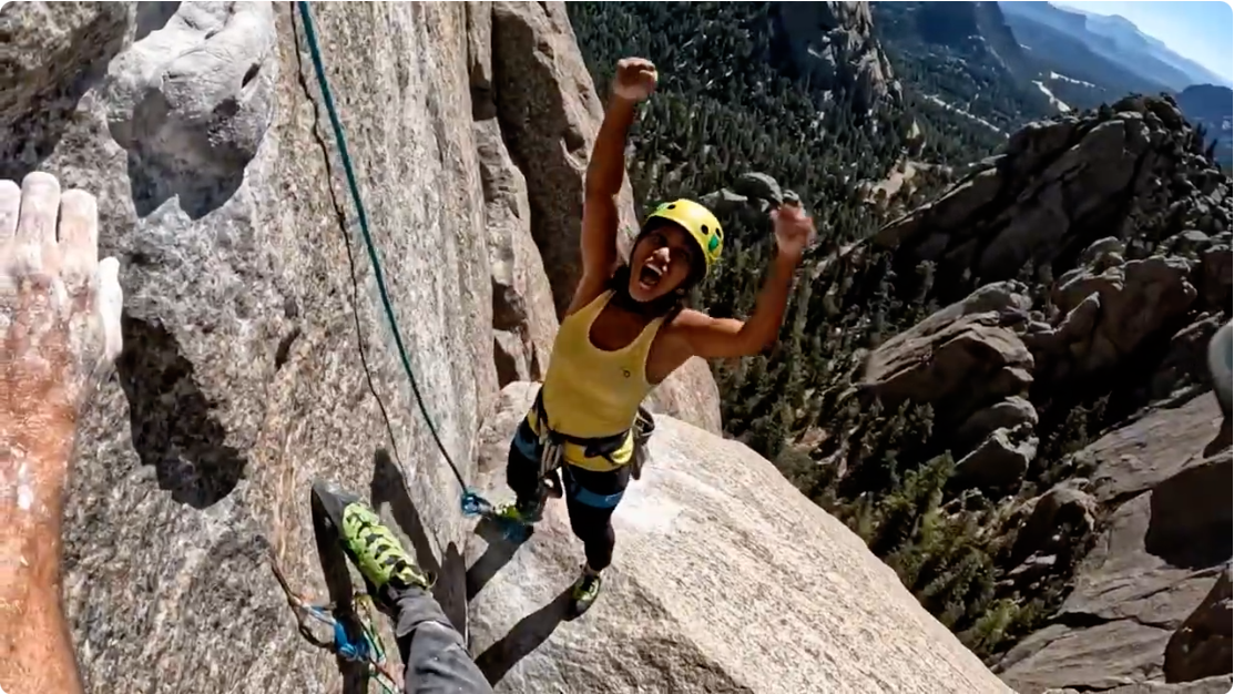 Adventurers - Rock climber celebrating on cliff with mountain landscape